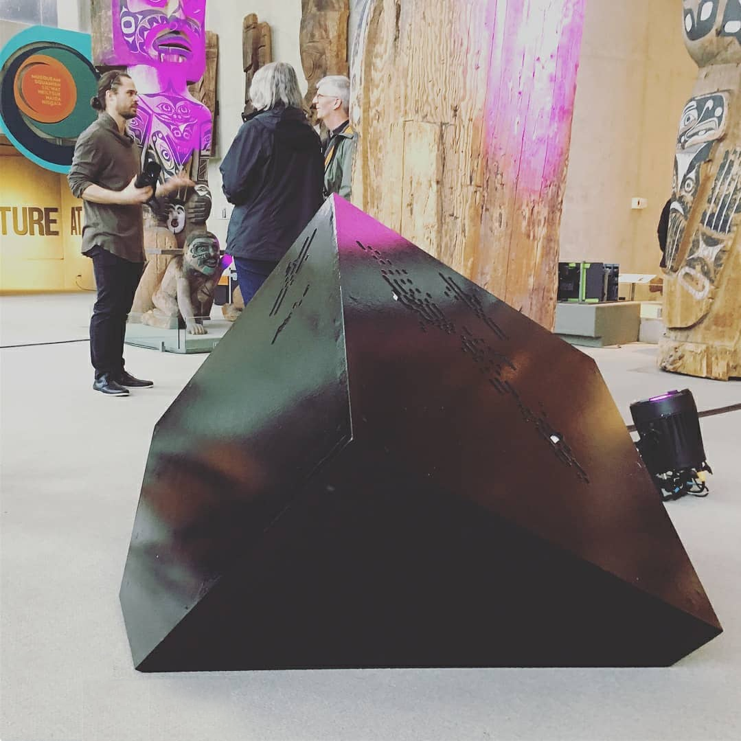 A large black cube, embedded in the ground